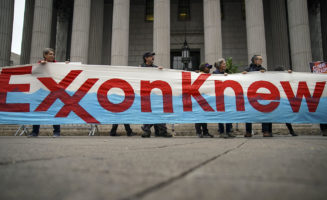 protestors hold up a sign that says exxon knew