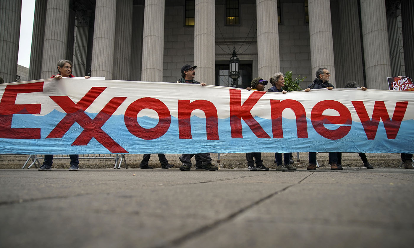 protestors hold up a sign that says exxon knew