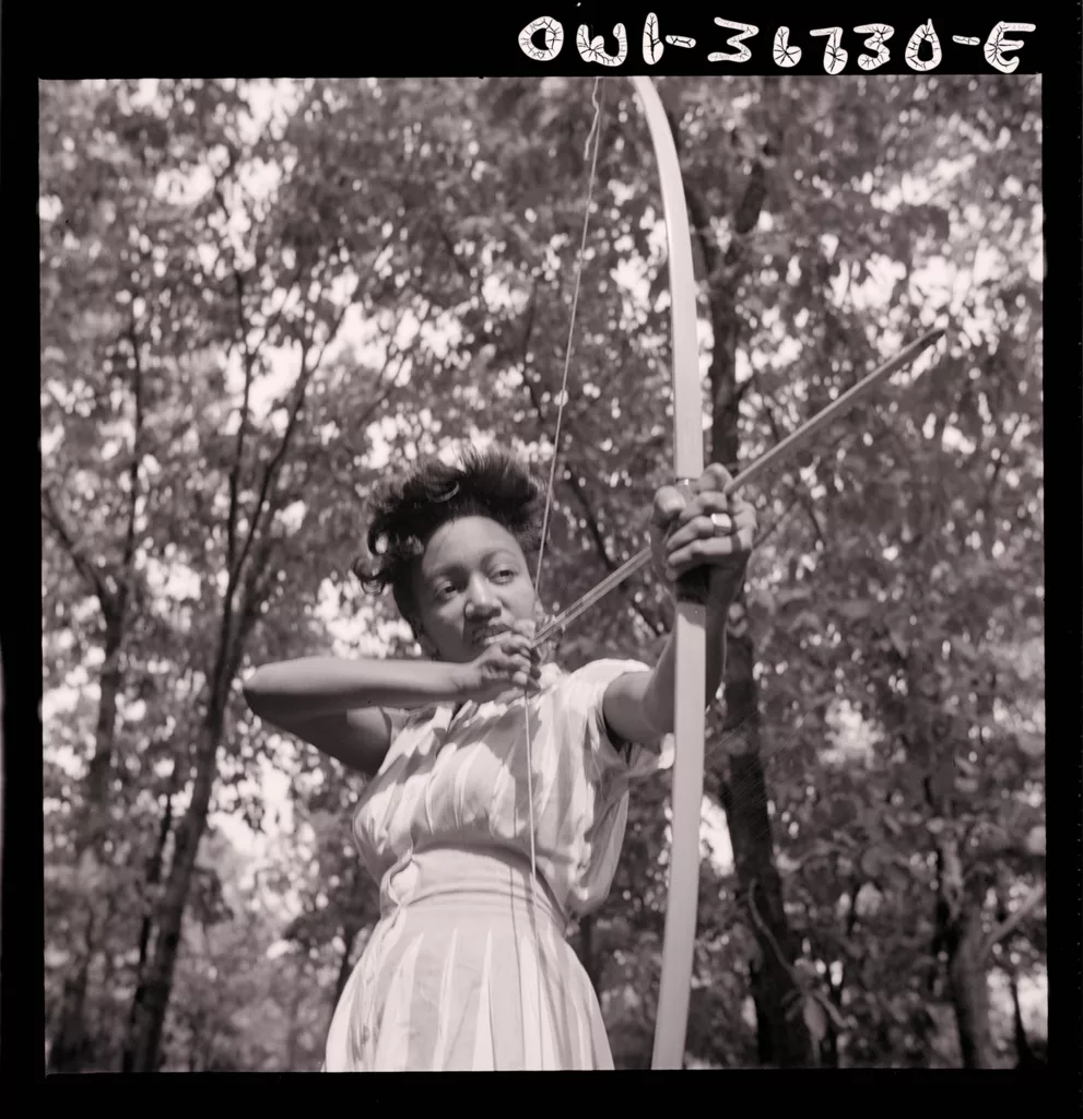 Loretta Gyles aims a bow and arrow at Camp Fern Rock in Bear Mountain, New York (1943).