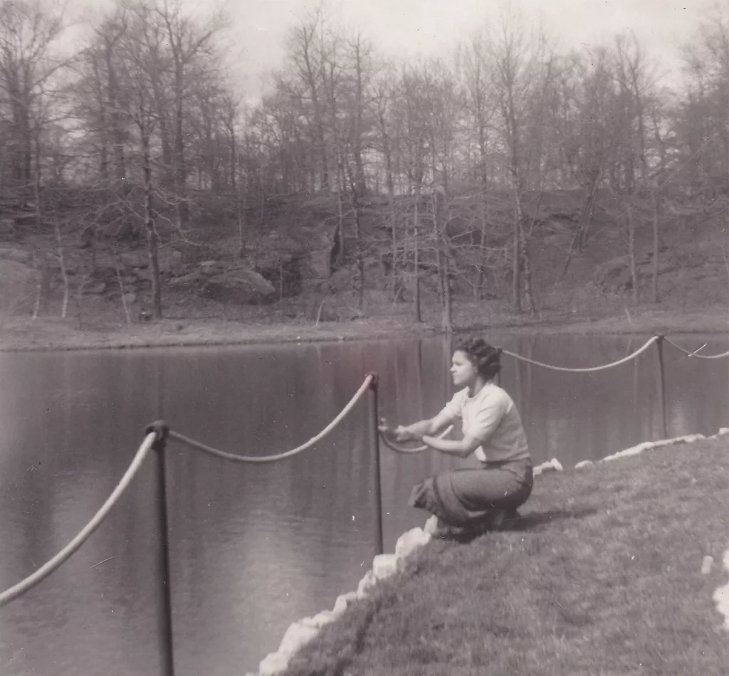 Carolyn Finney's mother kneels in front of a lake on the New York estate her parents "lovingly tended as caretakers for nearly 50 years."