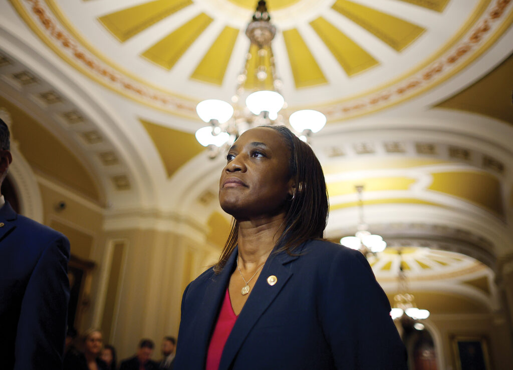 Sen. Laphonza Butler in a blue blazer stands in the portico of a government building