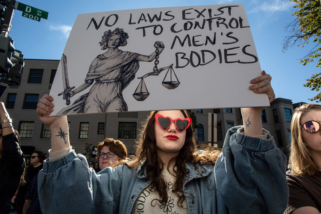 An abortion rights activist holds a protest sign with "No Laws Exist to Control Men’s Bodies" written on it. She and others gathered in front of the Heritage Foundation during the Women’s March.