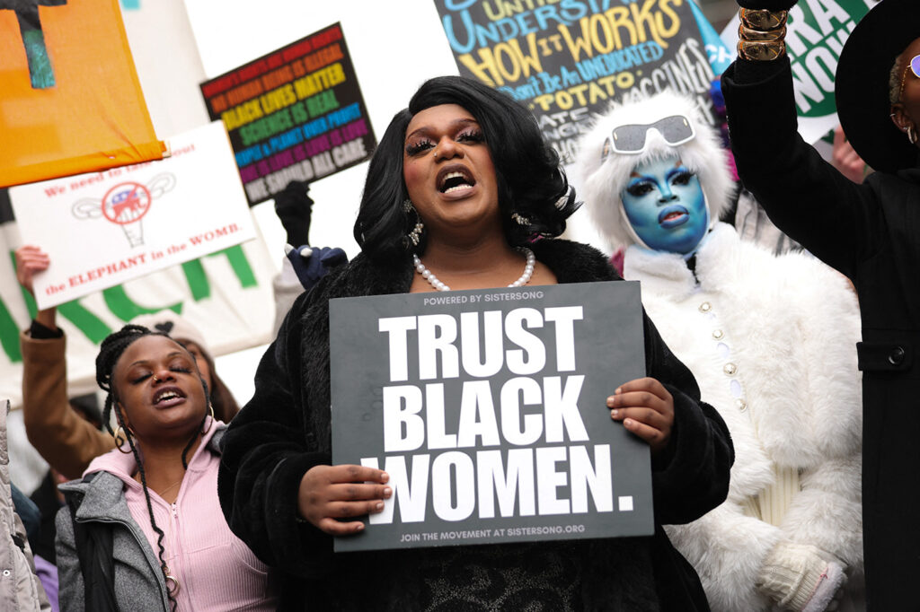 During the People’s March in Washington, D.C., held January 18, 2025, protesters held signs advocating for racial justice and intersectionality. In this photo, a black woman holds a sign from SisterSong, a reproductive justice organization, that reads "Trust Black Women"