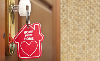 Key in lock with "Home Sweet Home" keychain. Photo by Shutterstock.