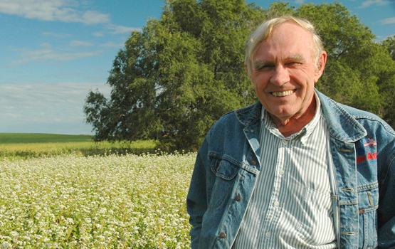 Fred Kirschenmann stands in a field.